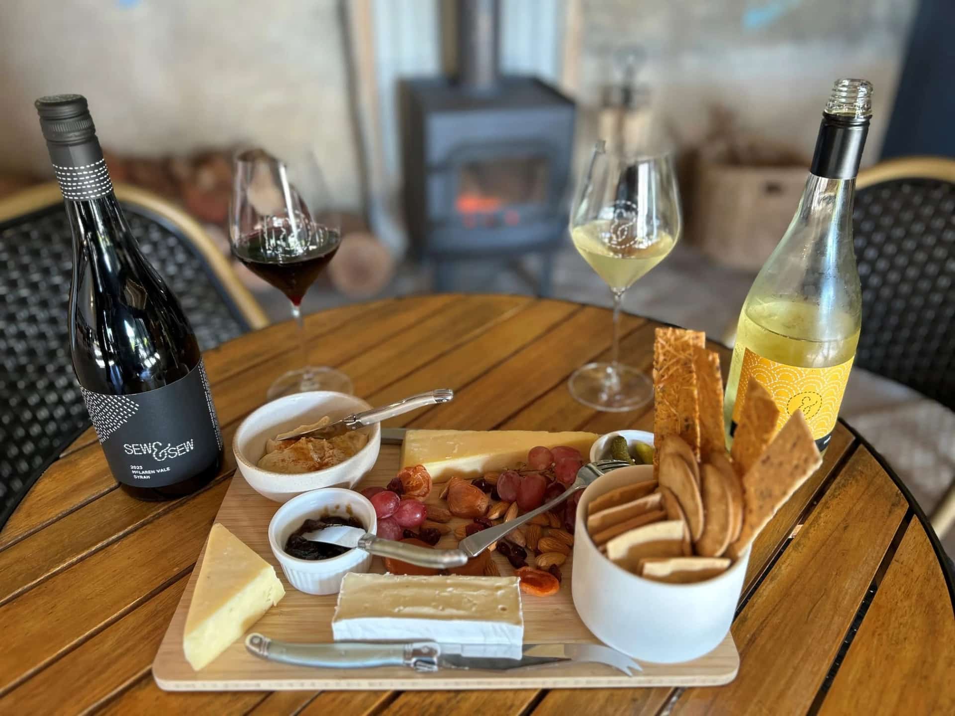 A cheeseboard, Sew & Sew Syrah and a white wine poured beside the cellar door fireplace
