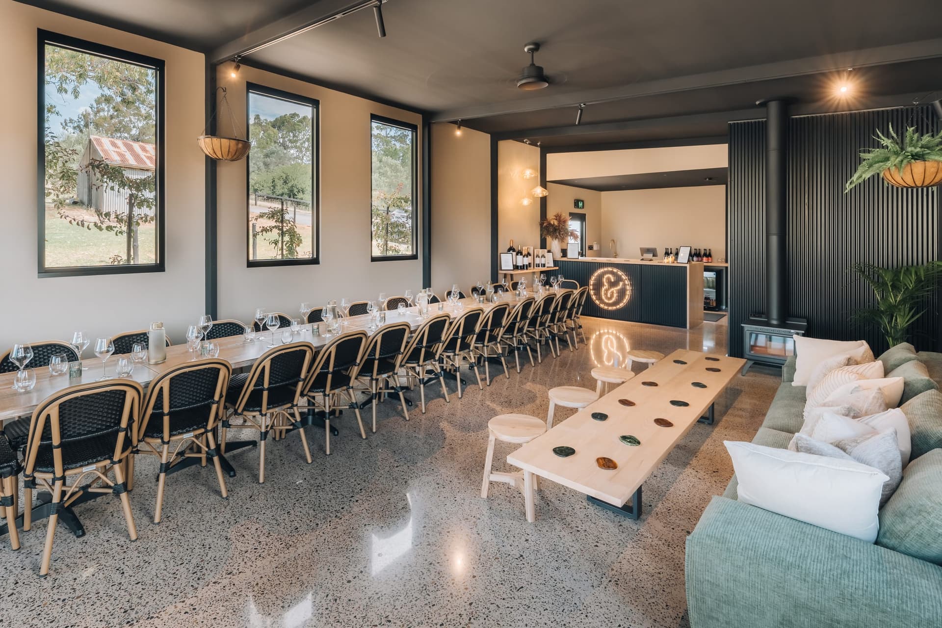 The event space set for a seated function, the bar and stitched ampersand at the far end