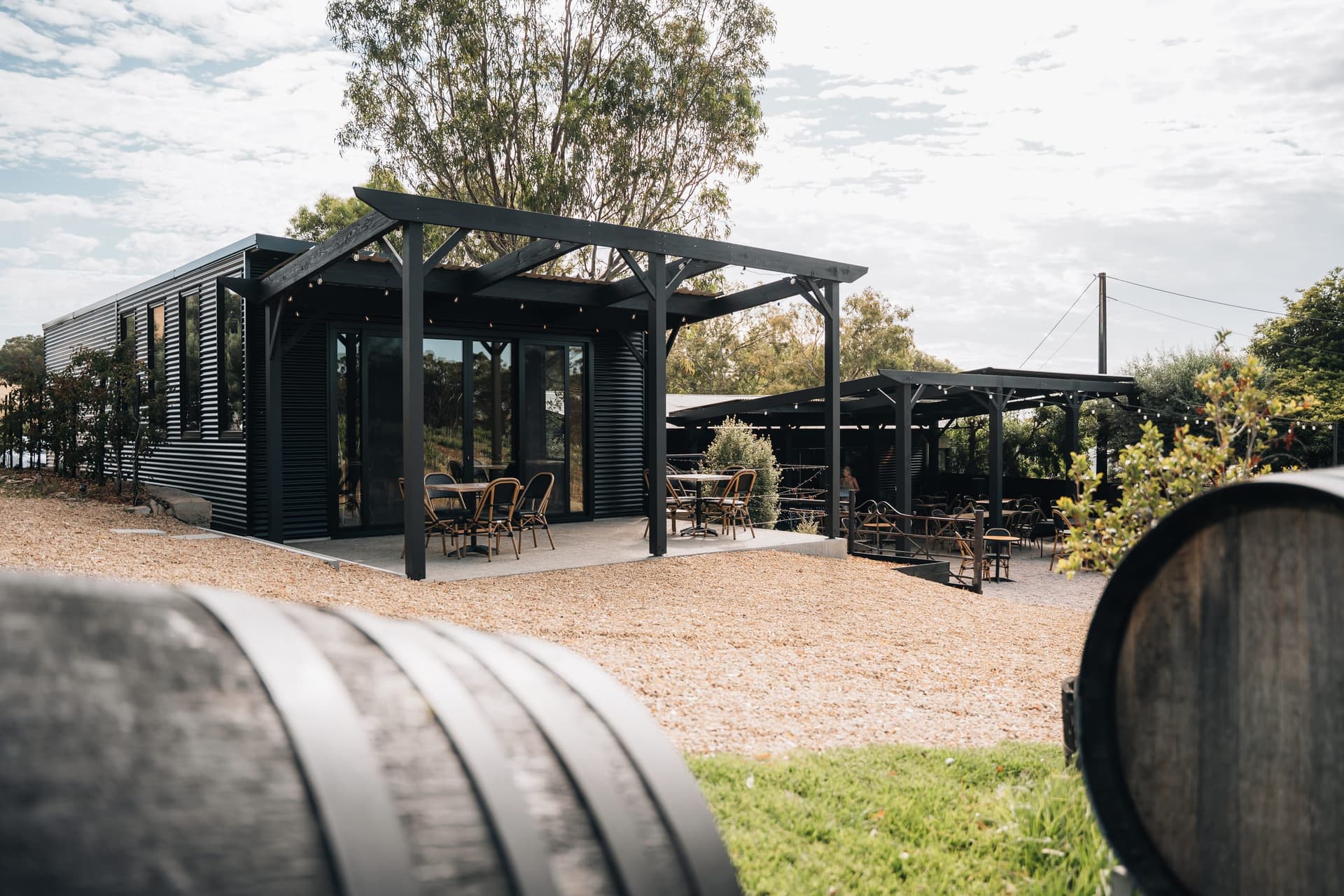 The black pergola and outdoor terrace beside the event space, wine barrels and vines beyond