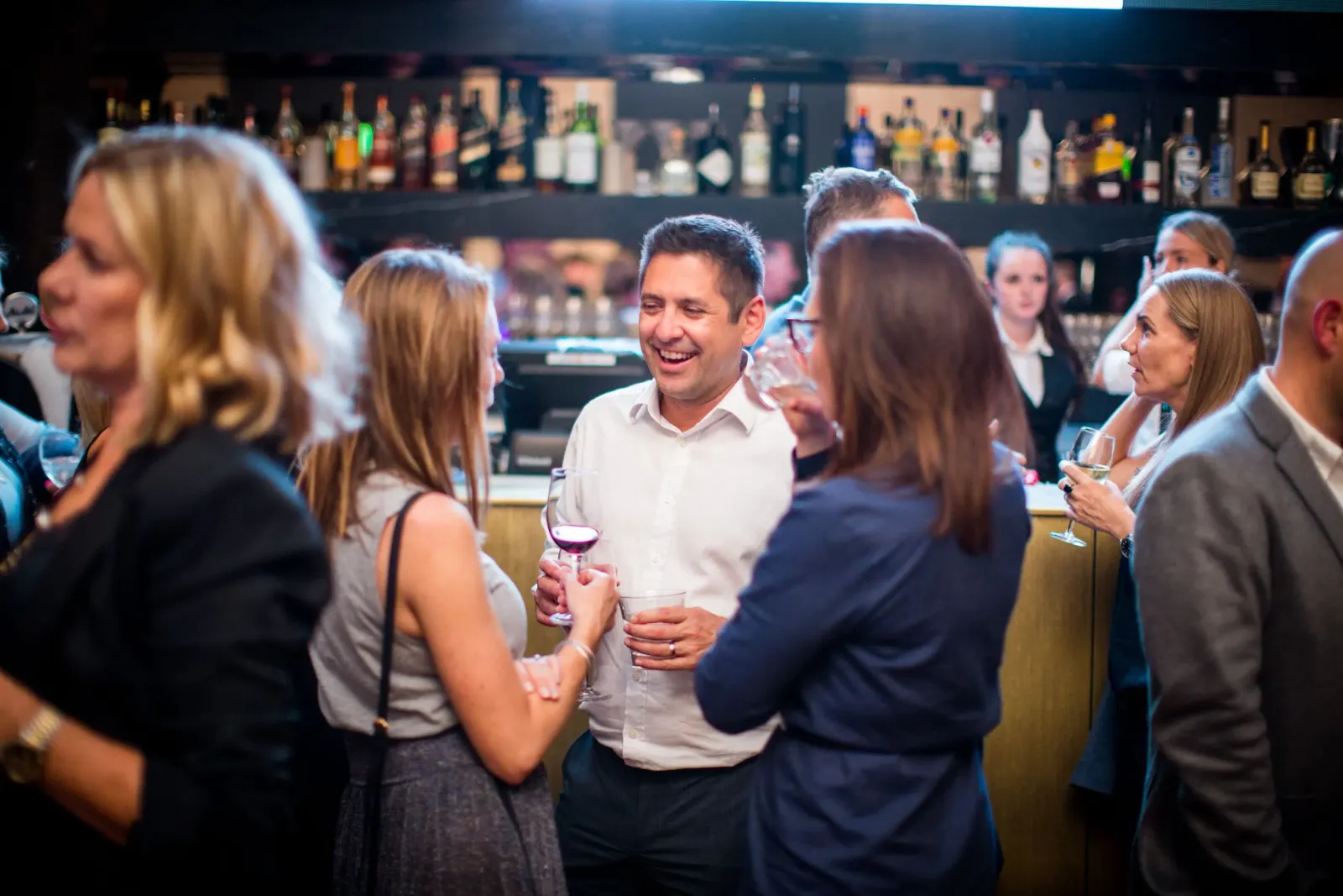 Guests laughing together at the bar at an earlier Gather & Yarn