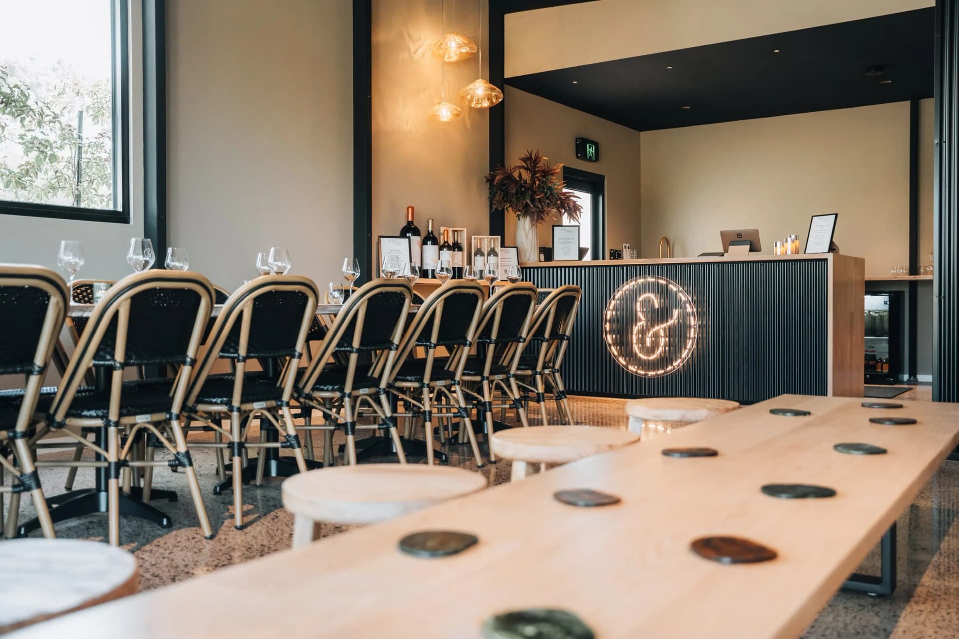 Inside the converted-dairy cellar door, tables set beneath the lit Sew & Sew ampersand
