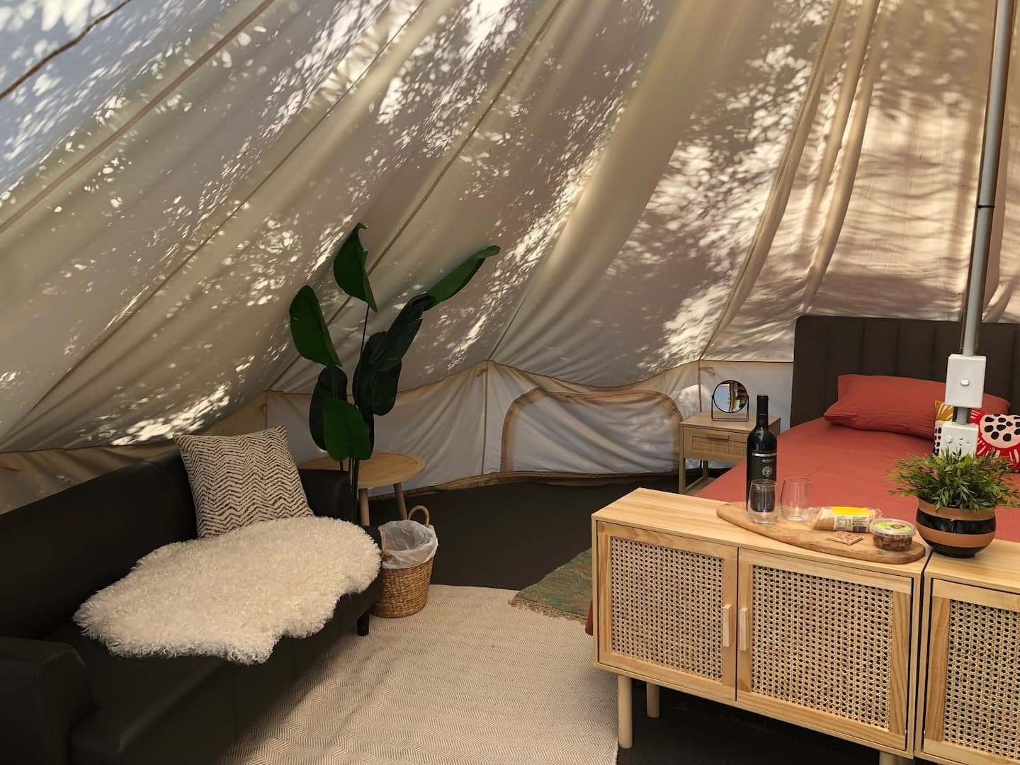 Inside the glamping tent: made bed, timber cabinets and a couch