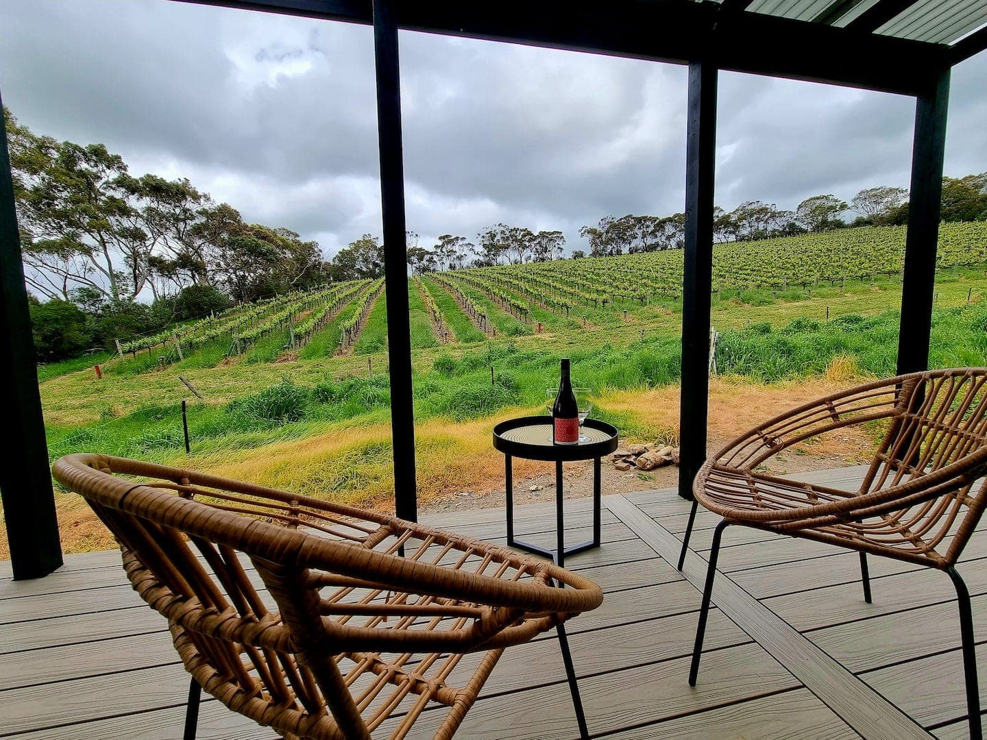 Two chairs and a bottle of wine on the tiny house deck, looking over the Alagna vineyard